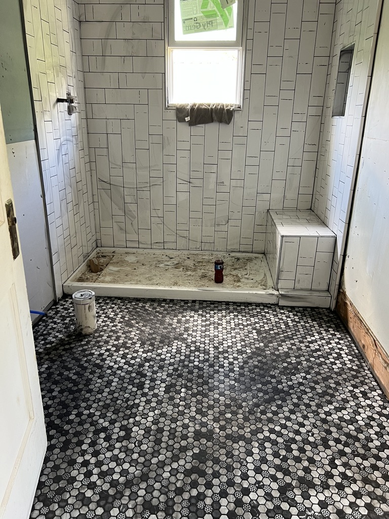 Bathroom remodeling in progress with shower tile and hexagonal floor