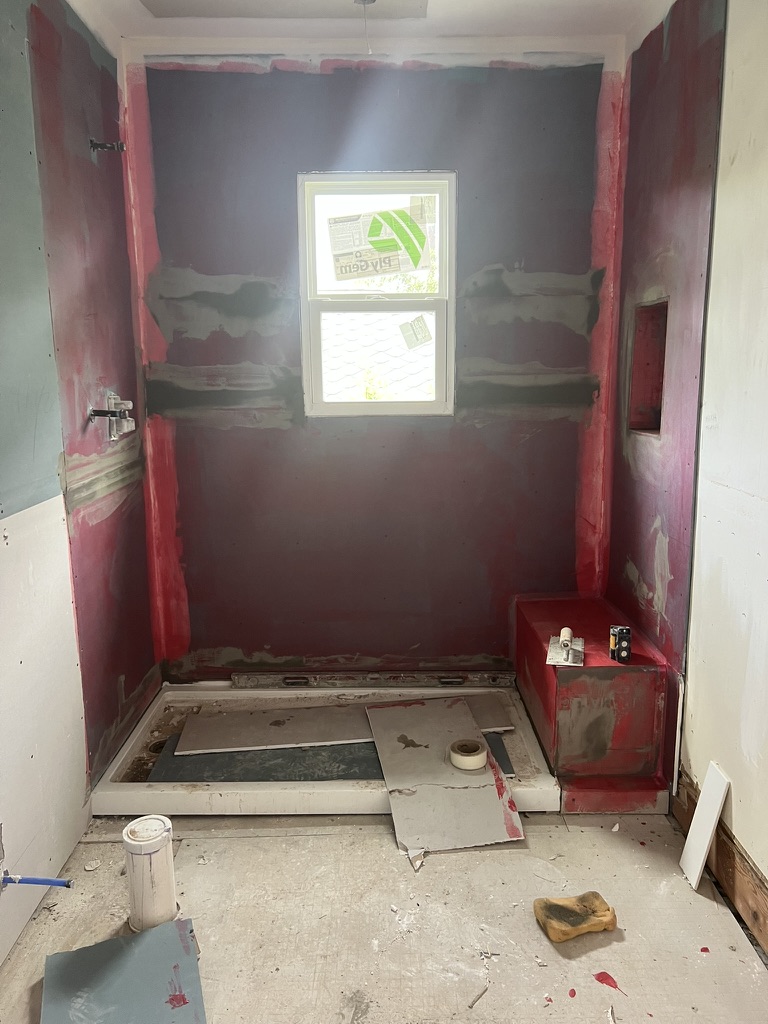 Bathroom remodeling during early progress with red waterproofing and shower preparation